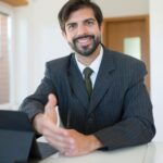 Real estate agent smiling in a modern office environment, ready for business transactions.